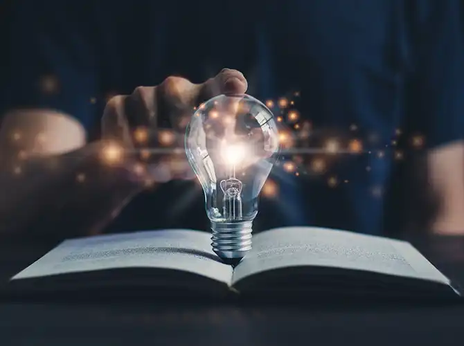 Symbolbild einer Glühlampe auf einem Buch.
